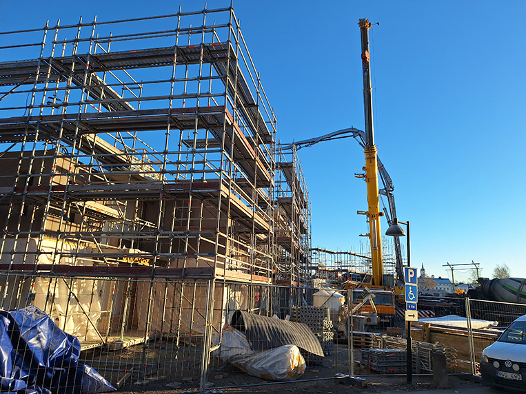 Bild visar byggställning runt väggar samt maskin för påfyllning av betong